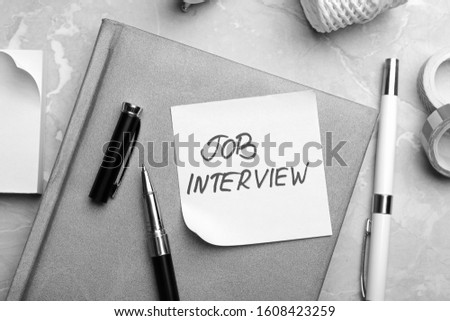 Reminder note about job interview and stationery on table, flat lay
