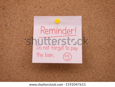 Reminder note attached to the board. Post-it. A paper note with a reminder about the payment of the current loan. Credit Reminder. 