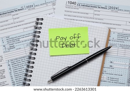 Reminder note with phrase Pay Off Debt, notebook and pen on documents, flat lay