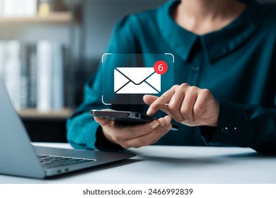 Reminder for unread emails: A businesswoman holds a mobile phone and taps on a new email notification icon. Internet technology. - Powered by Shutterstock