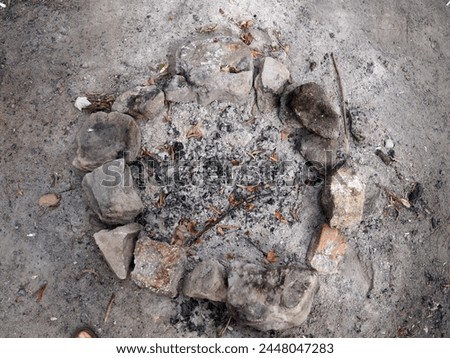 remnants of a campfire circled by stones outdoors.