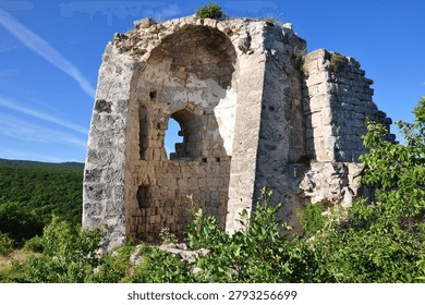 Remnants of an old defensive structure, featuring a large arched opening and exposed stone masonry, highlighting the historical and archaeological importance