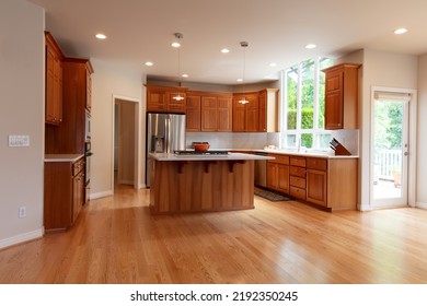 Remodeled kitchen in luxury home with island plus built in stove top, pendant lights, real red oak hardwood floors, cherry cabinets and stainless steel appliances  - Shutterstock ID 2192350245