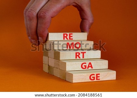 Remortgage loan symbol. Wooden blocks with the word Remortgage. Beautiful orange background, copy space. Businessman hand. Business, remortgage loan concept.