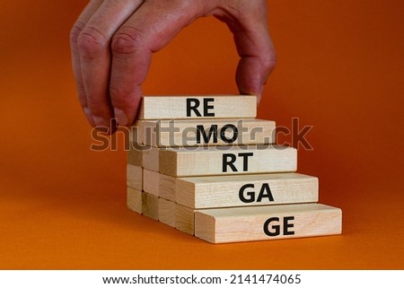 Remortgage loan symbol. Wooden blocks with the word Remortgage. Beautiful orange background, copy space. Businessman hand. Business, remortgage loan concept.