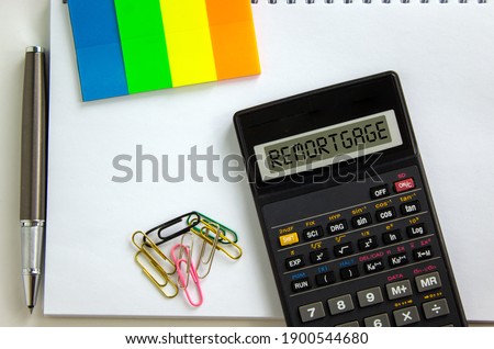 Remortgage symbol. Calculator with the word 'remortgage', white note, colored paper, paper clips, pen. Business and remortgage concept.