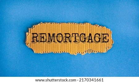 Remortgage symbol. The concept word 'remortgage' on the piece of cardboard. Beautiful blue background, copy space. Business and remortgage concept.