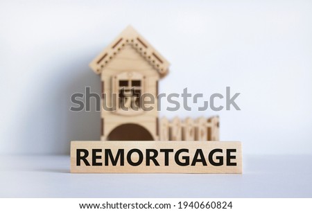 Remortgage symbol. Word 'remortgage' on wooden block. Model of a wooden house. Copy space. Business and remortgage concept. Beautiful white table, white background.