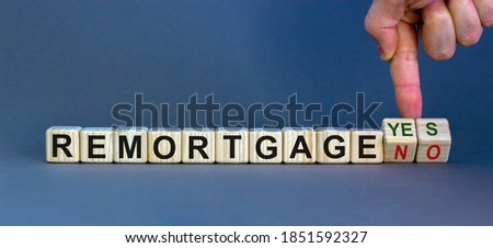 Remortgage yes or no. Male hand flips wooden cubes and changes the inscription 'remortgage no' to 'remortgage yes' or vice versa. Beautiful grey background, copy space.