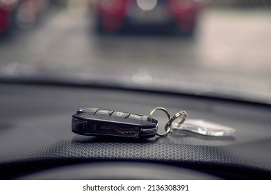 Remote car key on dash board in focus. Car park out of focus in the background. Transportation industry. - Shutterstock ID 2136308391