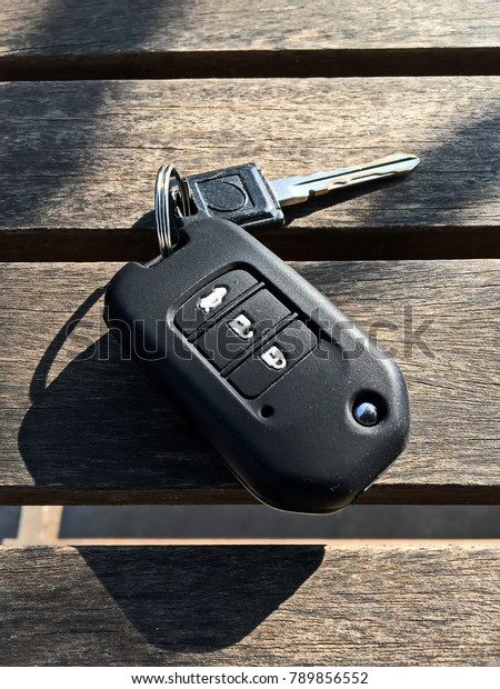 Remote car key\
with silicone cover isolated on wooden table background with\
morning sunlight rays. close up\
shot