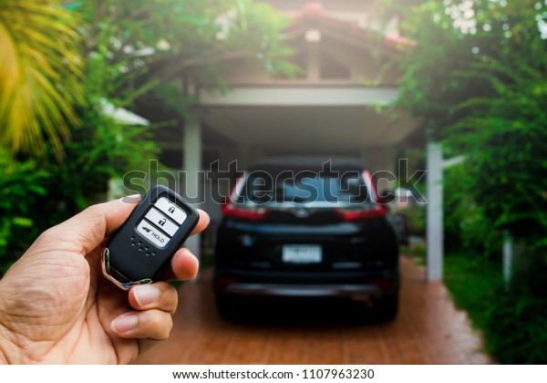 Remote\
car keys, and black car in the house\
background.