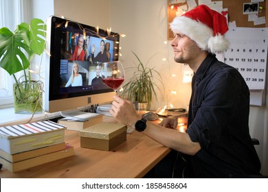 Remote Christmas Video Party. Family Zoom Call Celebrate New Year 2021 Online Video Conferencing. Young Man Wearing Red Santa Hat And Holding Red Wine. Virtual Meeting Conference Calling From Home