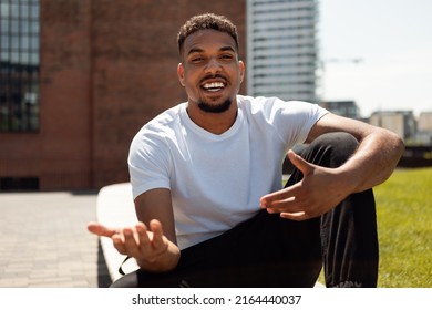 Remote Communicaton. Happy Black Man Making Video Call, Gesturing And Talking To Camera While Sitting Outdoors In Urban Area, Free Space