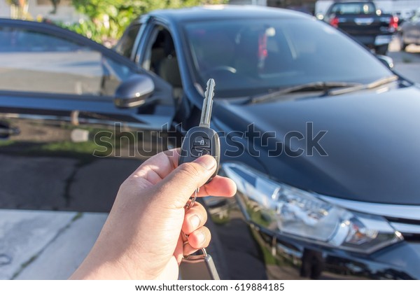 Remote control of car alarm systems in  hand with\
defocused car, close up