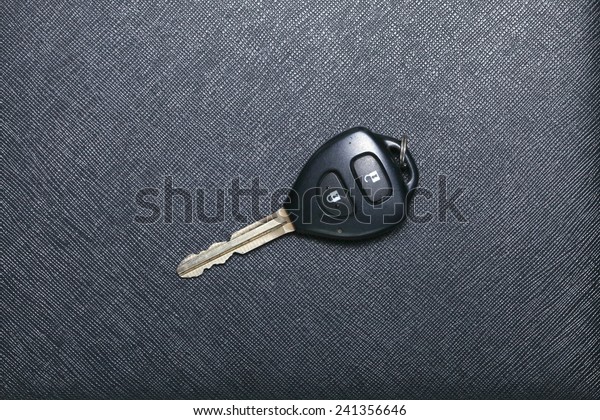 Remote control car key set put on black color\
leather surface background represent the car security system\
related equipment.