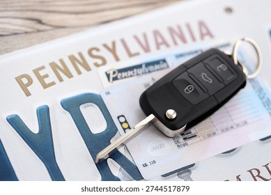 Remote control car keys on Pennsylvania license plate with driver license. Concept of driving in Pennsylvania. Reaching a driving permit