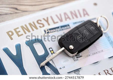 Remote control car keys on Pennsylvania license plate with driver license. Concept of driving in Pennsylvania. Reaching a driving permit