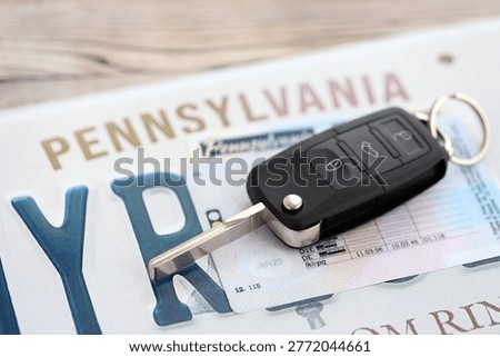 Remote control car keys on Pennsylvania license plate with driver license. Concept of driving in Pennsylvania. Reaching a driving permit