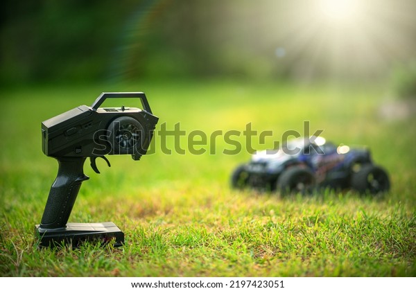 Remote\
control of the car model. Radio-controlled car on a green frame in\
the park. Active outdoor games.Electronic\
toys.
