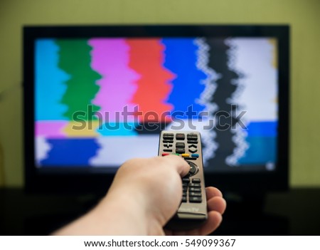 Remote control in hand in front of TV. Couch potato. No signal screen banner.