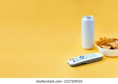 Remote Control, Nachos And Can Of Beer On Yellow Background. Concept Of Family Watching Movies And TV Shows. Selective Focus, Copy Space