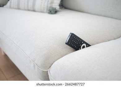 Remote control on a light gray sofa cushion. lost remove control concept 