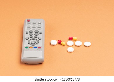remote control and tablets on an orange background. taking pills during illness
