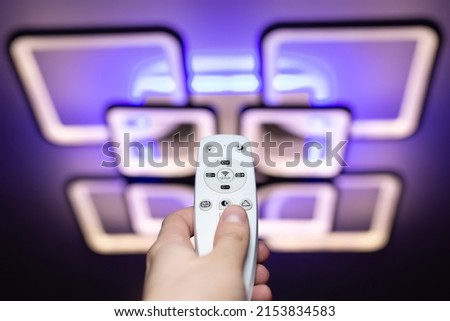 Remote control that controls the light. Neon chandelier on the ceiling.