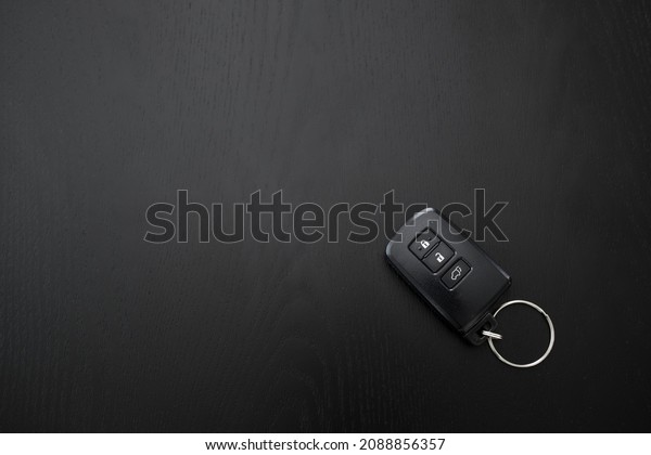 Remote controlled car key on the black wooden\
background, top view.