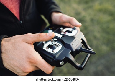 Remote Controller In Male Hands Close-up. Unrecognizable Man Holding Transmitter And Piloting Some Vehicle. Drone, Rc Car Or Helicopter Running. Leisure, Hobby, Entertainment Concept