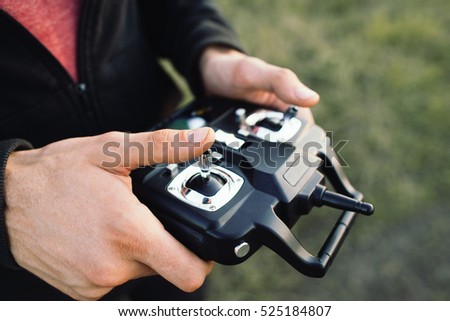 Remote controller in male hands close-up. Unrecognizable man holding transmitter and piloting some vehicle. Drone, rc car or helicopter running. Leisure, hobby, entertainment concept
