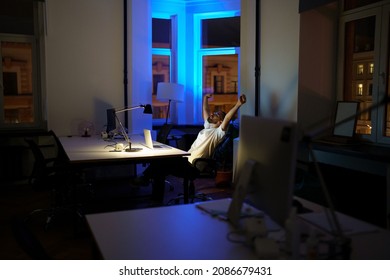 Remote creative designer have rest from overtime work sit in chair stretching arms relaxing. Tired male small business owner or manager workaholic refreshing at workplace during night shift in office - Shutterstock ID 2086679431