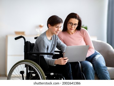 Remote education concept. Cheerful disabled teenager in wheelchair making online home assignment with his mother indoors. Cool impaired adolescent with laptop studying together with private tutor - Powered by Shutterstock