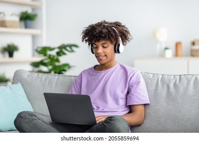 Remote Education. Cool Black Teen Guy In Headphones Having Online Lesson, Participating In Webinar On Laptop Indoors. African American Youth Studying From Home During Covid Quarantine