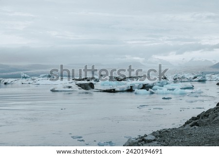Remote Iceland geographic background of black sand beach and isolated glacier lagoon with still water and floating icebergs travel tourism landmark 