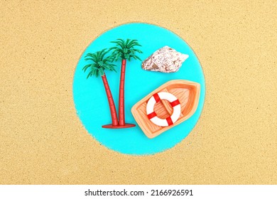 Remote Island Summer Vacation Background Made From Toy Palm Trees, Sea Shell And Tiny Boat Framed With Sand On Blue.