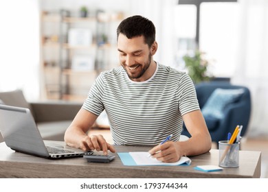 Remote Job And Business Concept - Happy Smiling Man With Papers, Calculator And Laptop Computer Working At Home Office