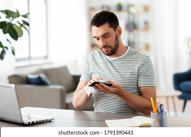 remote job, business and disinfection concept - man cleaning smartphone with antiseptic wet wipe at home office - Powered by Shutterstock