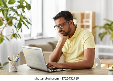 Remote Job, Technology And People Concept - Bored Or Sad Young Indian Man In Glasses With Laptop Computer Working At Home Office