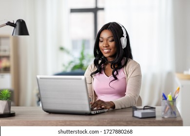 remote job, technology and people concept - happy smiling african american young woman in headphones with laptop computer working at home office - Powered by Shutterstock