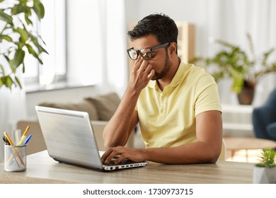 remote job, technology and people concept - tired young indian man in glasses with laptop computer working and rubbing his nose bridge at home office - Shutterstock ID 1730973715
