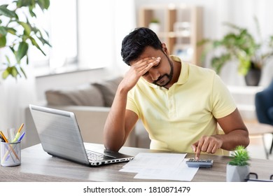 remote job, technology and people concept - stressed young indian man with calculator and papers working at home office - Shutterstock ID 1810871479