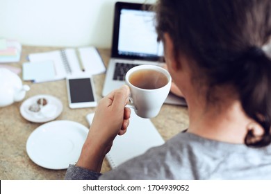 Remote Learning Or Work. Worker Having Break,  Browsing Laptop With Cup Tea. Closeup Of Man Hands With Cup Of Tea.