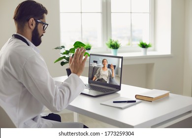 Remote Medical Consultation. A Male Doctor Consults A Woman Has A Video Call Conference Computer Monitor Sitting In A Clinic Office.