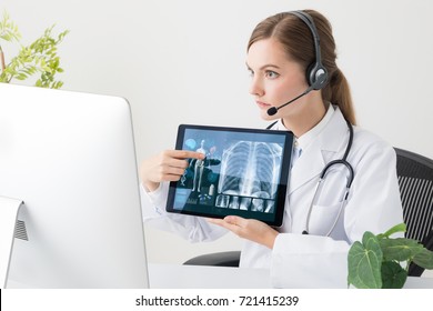 Remote Medicine Concept. Young Woman Doctor Talking With A TV Phone.