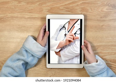 Remote Online Telemedicine. A Child In Home Clothes With A Tablet In His Hands. On The Screen Video Consultation With The Doctor. Recommendations For Treatment.
