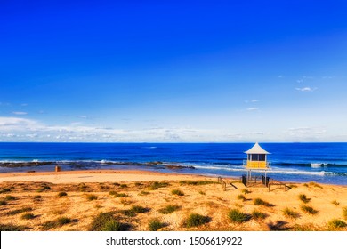 Remote Sandy Beach On Australian Pacific Coast With Lifeguards Life Savers Observation And Watch Hut Overlooking Beach Goers In Rolling Waves Of Open Sea.