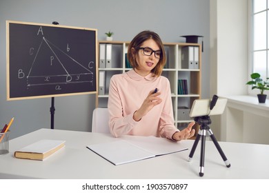 Remote Teaching. College Professor Or School Math Teacher Having Online Class, Using Mobile Phone With Tripod. Smart Young Woman In Glasses Explaining Geometry Problem In Virtual Lesson Via Video Call