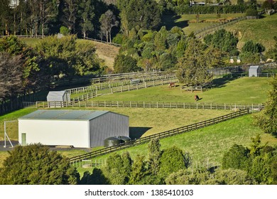 Remote view of white shed and green paddocks of a hill